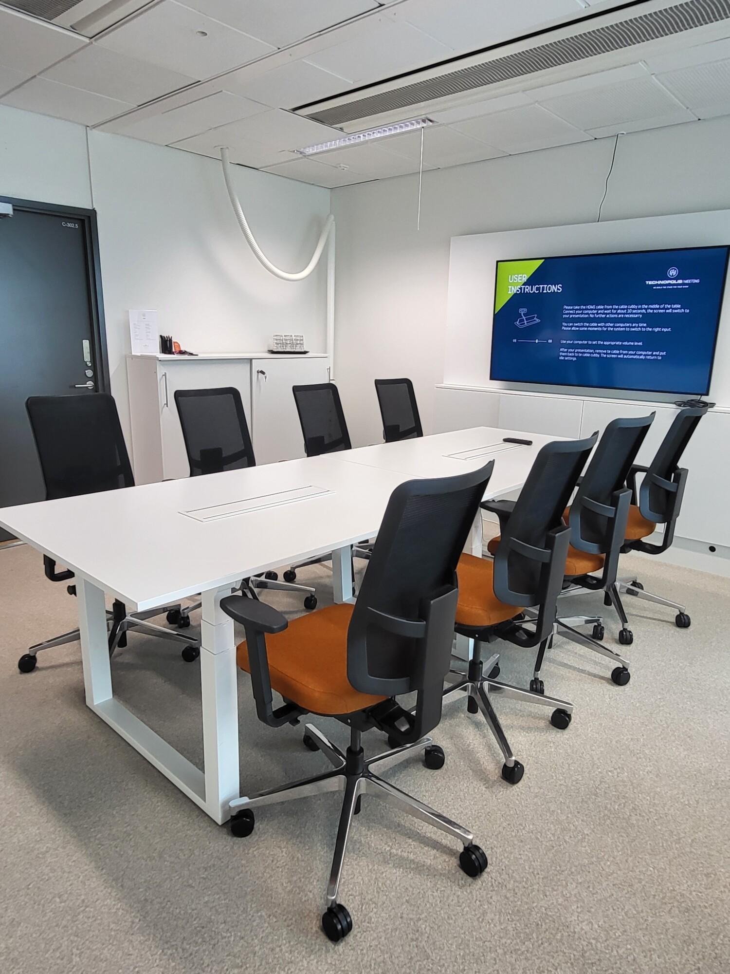 A stylish meeting room on the third floor, with a window overlooking a cozy and bright restaurant. The room features a boardroom-style table for 8 people, wireless internet access, an LCD screen, and a flip chart.